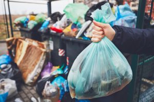 Hand,With,Garbage,Against,Full,Trash,Cans,With,Rubbish,Bags